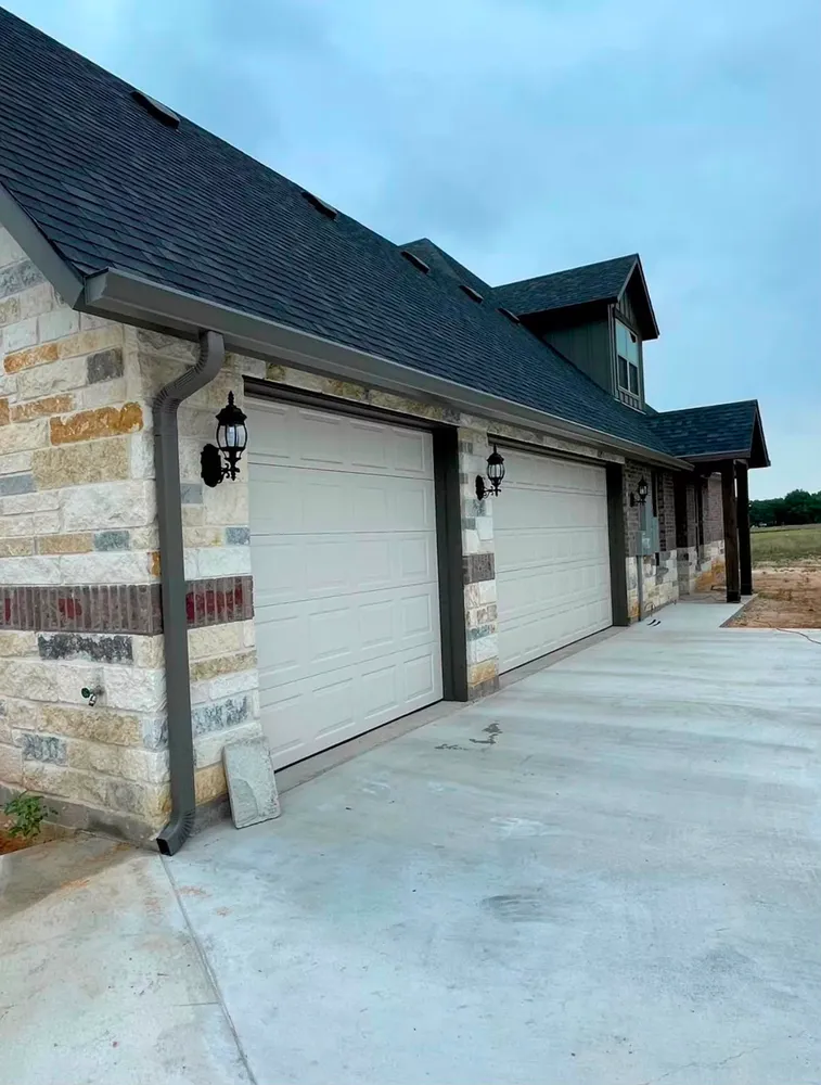 New bronze seamless gutters and downspouts on a stone home Frisco TX