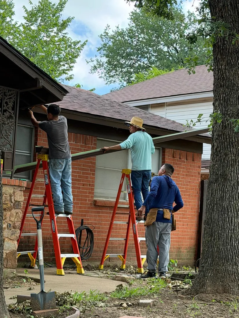 Crew installing seamless gutters on a Dallas Fort Worth brick home
