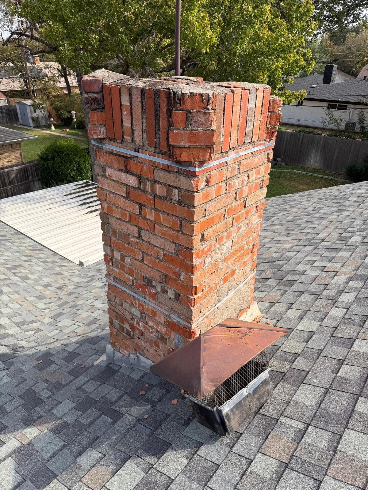 Chimney before rebuild — crumbling crown, spalling brick and rusted cap — Dallas TX