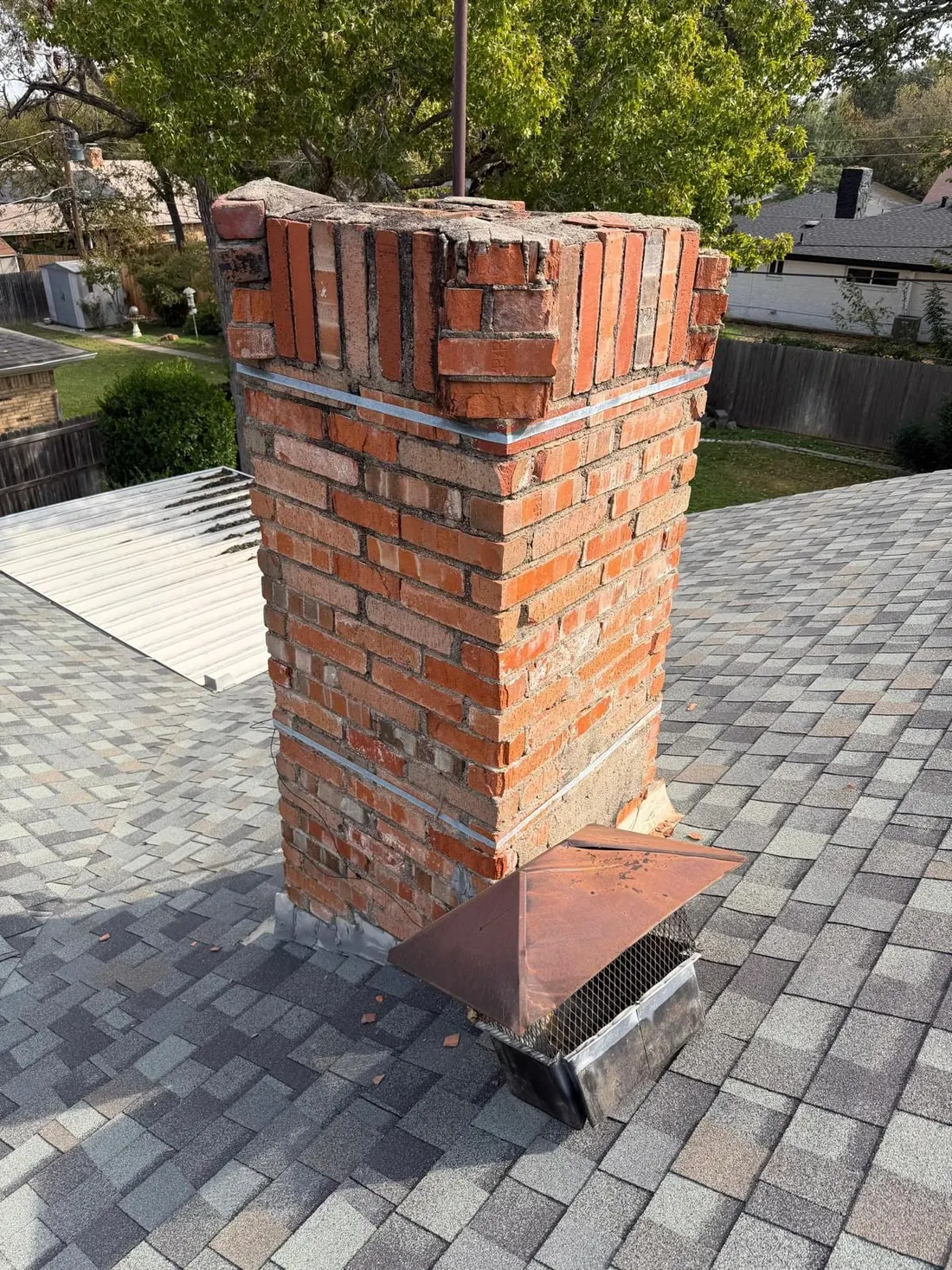 Chimney before rebuild — crumbling crown, spalling brick and rusted cap — Dallas TX