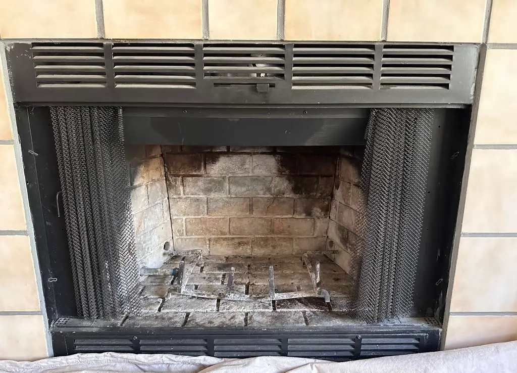 Fireplace before cleaning — dirty firebox with old grate and ash buildup — Dallas TX